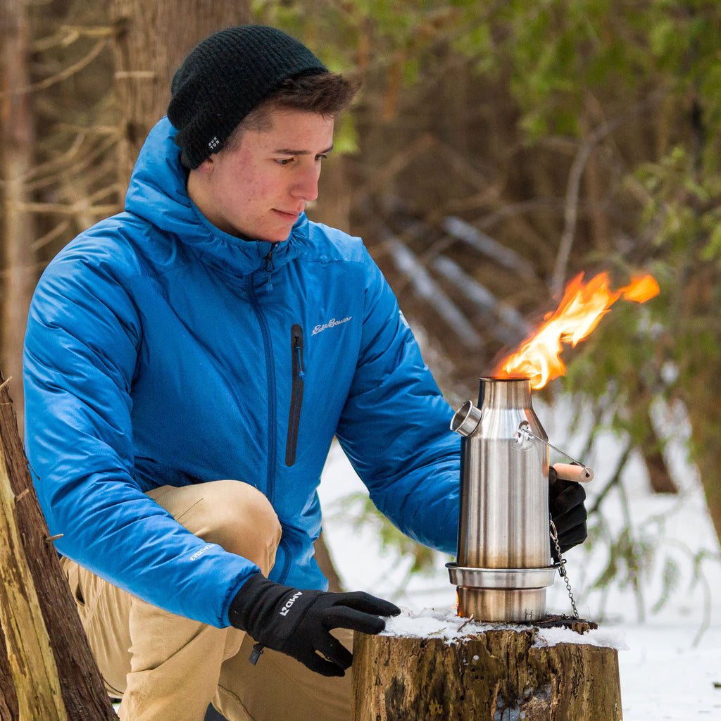 Man in blue jacket lighting a Kelly Kettle Stainless Steel Base camp 1.6l