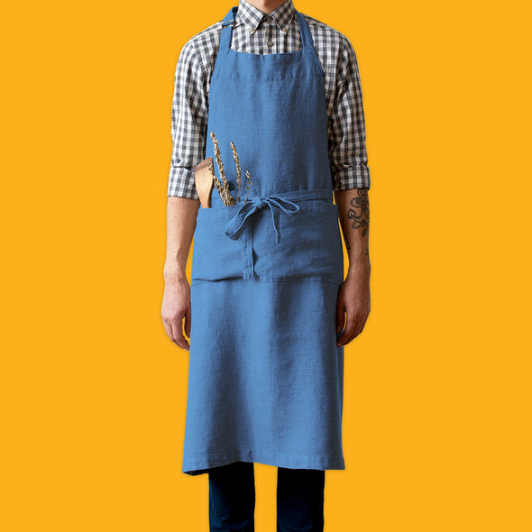 Man in check shirt wearing a blue washed linen chef apron from Linen Tales