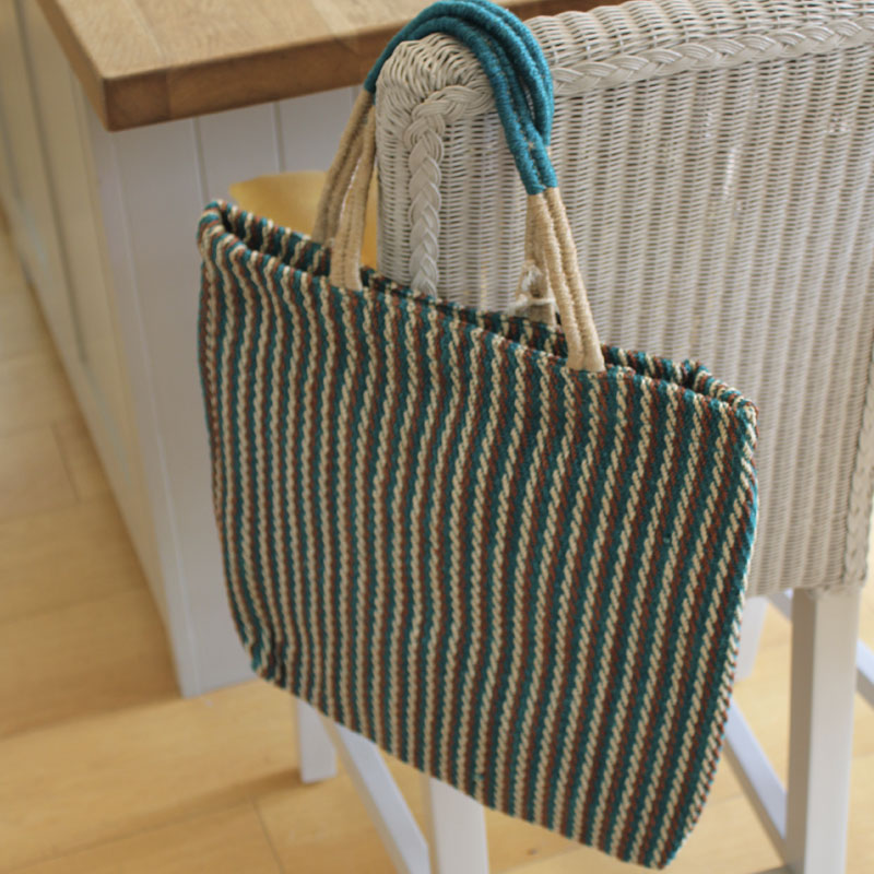 Turtle Bags Teal Striped Jute Bag Hanging on the back of a chair